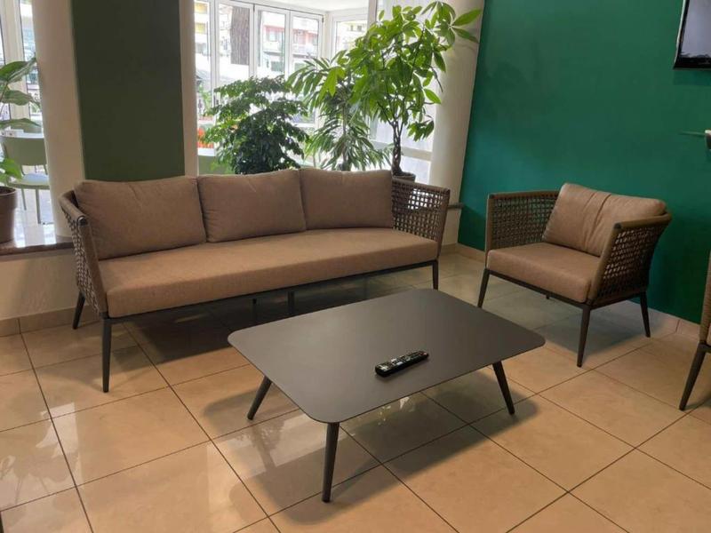 Espace lounge moderne avec canapé, fauteuil et table basse près de grandes fenêtres.