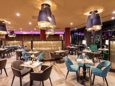 Modernes Restaurant mit stilvollen Lampen und komfortablen Stühlen in Blau und Braun.