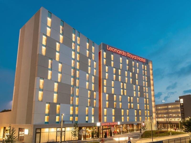 Modernes Hotelgebäude mit vielen beleuchteten Fenstern bei Abenddämmerung.