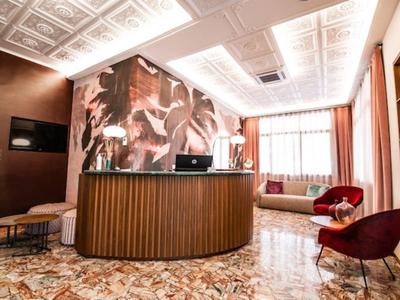 Helle Hotellobby mit rundem Empfangstresen, gemütlichen Sesseln und großzügigen Fenstern.