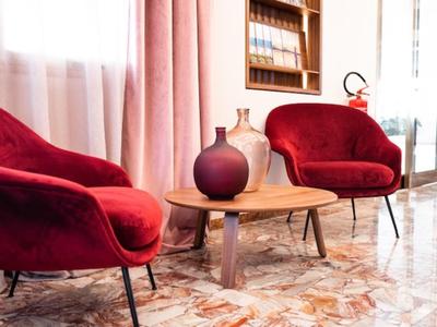 Dwa czerwone fotele z małym drewnianym stolikiem i dekoracyjnymi wazonami w jasnym pomieszczeniu.