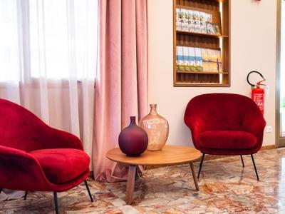 Due poltrone in velluto rosso con un piccolo tavolo di legno e vasi decorativi in una stanza accogliente.