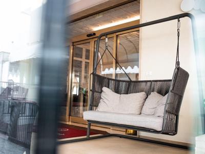 Nowoczesny, elegancki fotel bujany z poduszkami przed wejściem do hotelu lub restauracji.