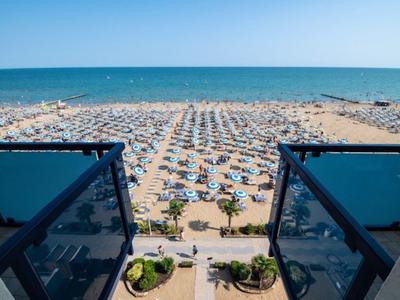 Widok z balkonu na plażę z wieloma parasolami i leżakami nad morzem