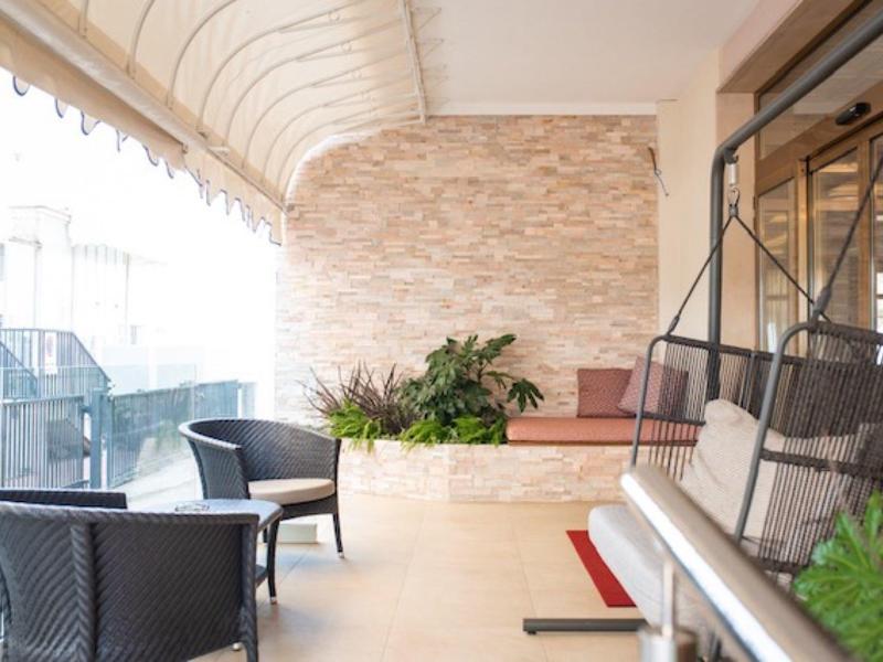 Jasny zadaszony taras z meblami i roślinami w jasnym wnętrzu.