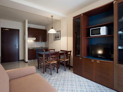 Gezellige woonkamer met eettafel, kitchenette en kast met magnetron en tv.