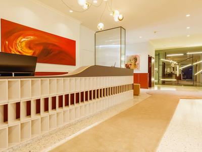 Moderner Hotellobby-Empfang mit elegantem Tresen und roter Wanddekoration.