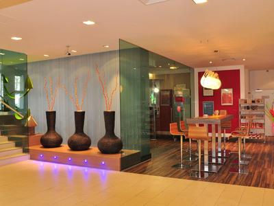 Moderner Hotel-Lobbybereich mit Vasen, Glaswänden und Essbereich mit Holzfußboden.