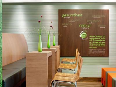 Moderner Sitzbereich mit Holzmöbeln, grünen Vasen und gemütlichen Stühlen in einem Hotel.