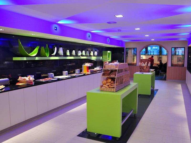 Moderne Hotellobby mit Buffet und grünen Sitzgelegenheiten unter blauer Deckenbeleuchtung