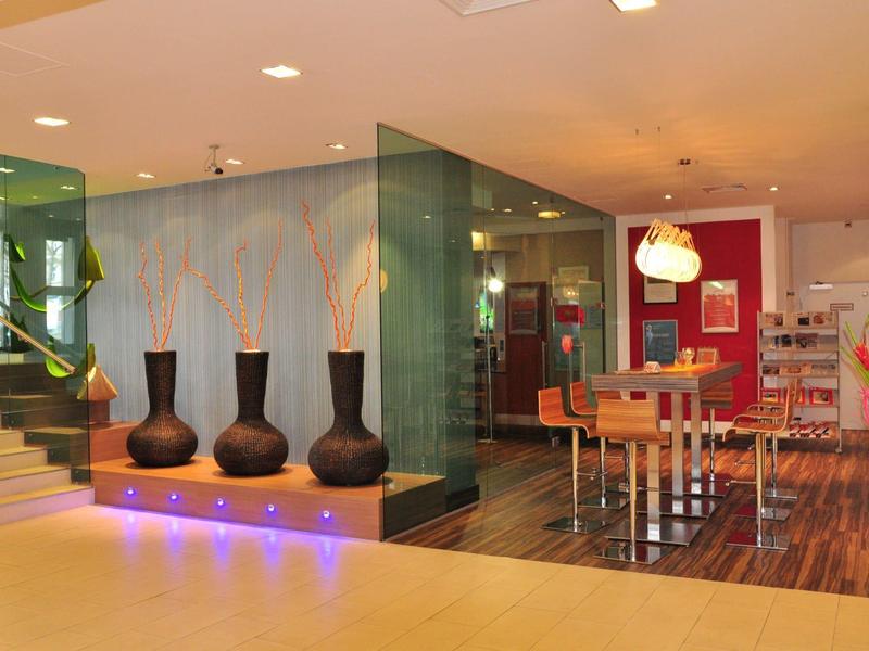 Moderner Hotel-Lobbybereich mit Vasen, Glaswänden und Essbereich mit Holzfußboden.