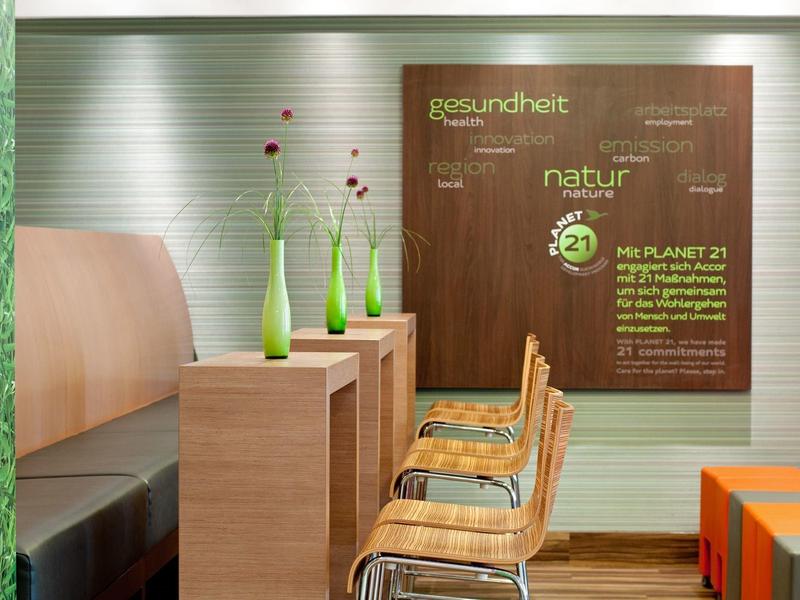 Moderner Sitzbereich mit Holzmöbeln, grünen Vasen und gemütlichen Stühlen in einem Hotel.