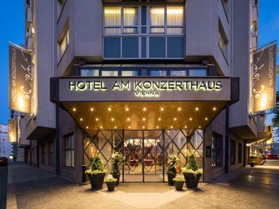 Moderne Hotelfassade mit beleuchtetem Eingangsbereich und großen Fenstern bei Abenddämmerung.