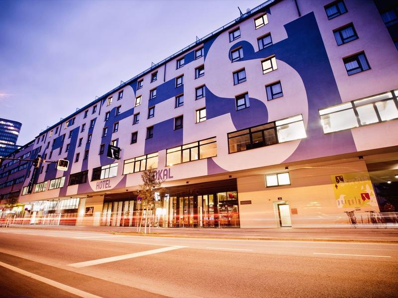 Modernes Hotelgebäude mit großem Schriftzug und beleuchteten Eingängen bei Dämmerung