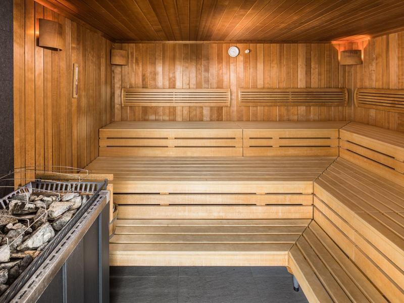 Innensauna mit Holzbänken und einem Heizgerät mit Steinen im Vordergrund