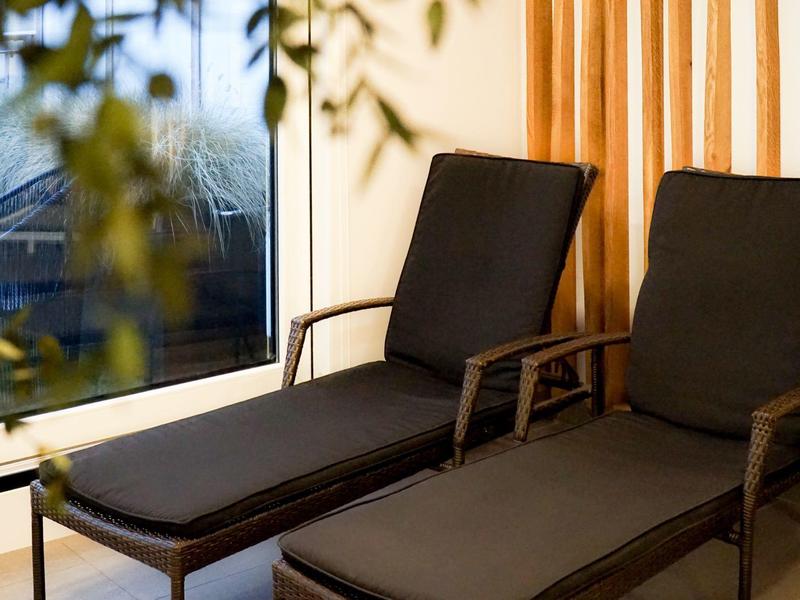 Zwei schwarze Liegestühle neben einem Fenster mit Vorhängen in einem Hotelzimmer.