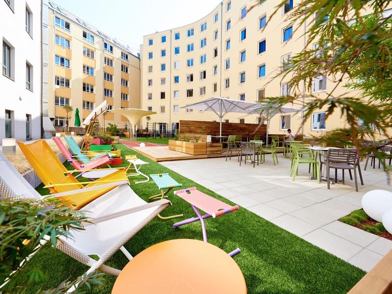 Innenhof eines Hotels mit Liegestühlen, Tischen und Sonnenschirmen in moderner Umgebung