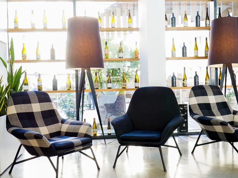 Gemütlicher Sitzbereich mit modernen Sesseln und Stehlampen vor einem Regal mit Flaschen.