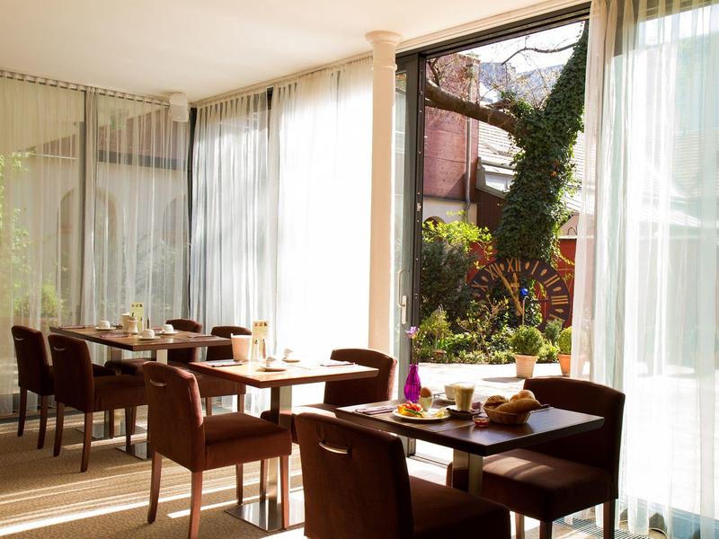 Hell eingerichteter Essbereich mit braunen Stühlen und Tischen, mit Blick auf einen grünen Garten.