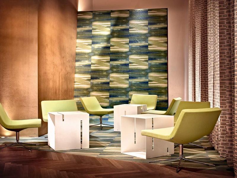 Moderner Wohnraum mit grünen Sesseln, weißen Beistelltischen und bunter Wandgestaltung.