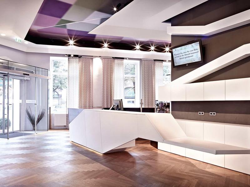 Moderner Empfangsbereich mit großem weißen Tresen, braunen Wänden und Glas-Eingangstür.
