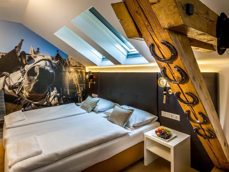 Gemütliches Schlafzimmer mit Schrägdach, großen Betten, Wandbild und holzverzierten Balken.