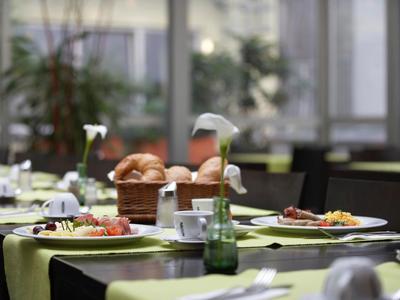 Gedeckter Tisch mit Teller, Besteck, Gläsern und Brotkorb in einem hellen Restaurant.