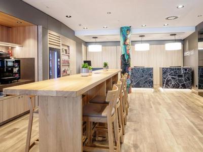 Moderner Gemeinschaftsbereich mit Holztheke, Barhockern und stilvoller Beleuchtung.