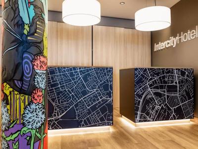 Moderner Hotel-Empfangsbereich mit beleuchteten Tresen und bunter Wandkunst.