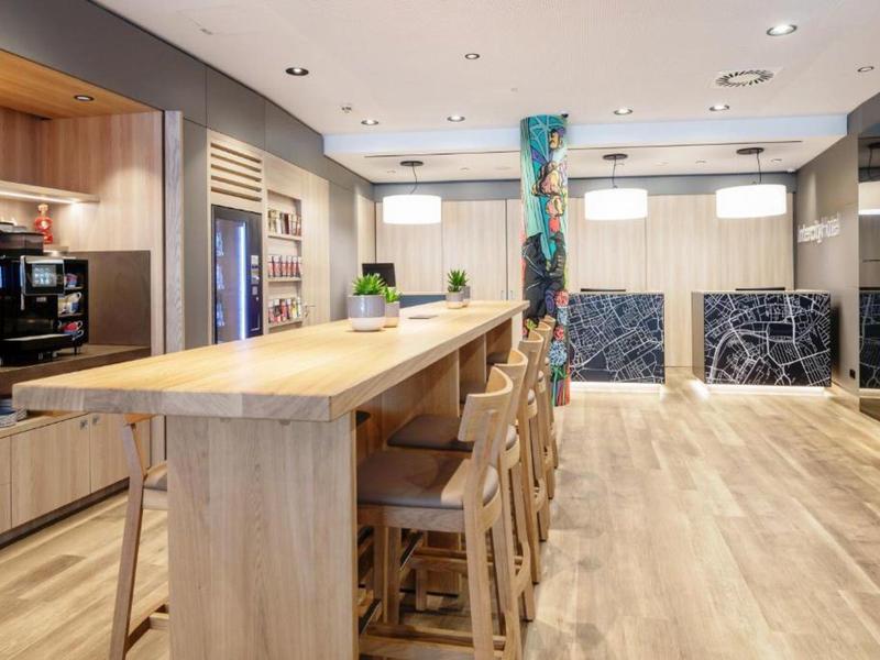 Große moderne Küche mit Holzarbeitsplatte, Barhockern, Edelstahlgeräten und heller Holzboden.