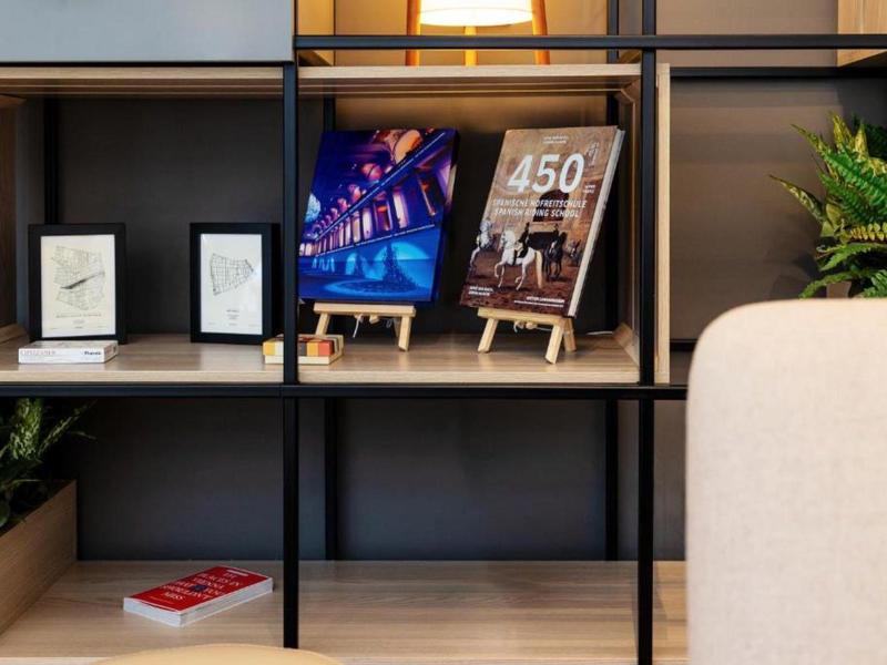 Moderner Regal mit Büchern, Pflanzen, Poster und dekorativen Rahmen in warmem Licht.