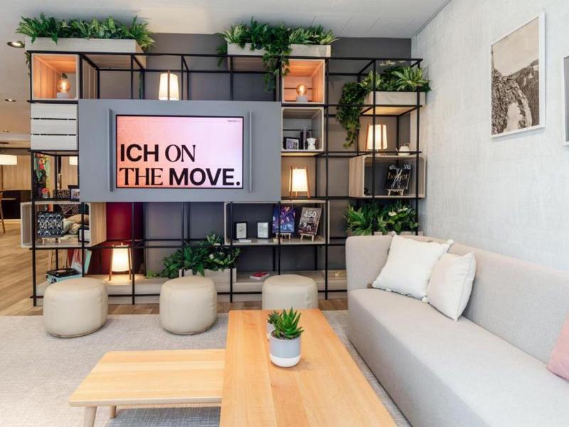 Modernes Wohnzimmer mit grauem Sofa, Holztisch, TV-Regal und grünen Pflanzen für gemütliche Atmosphäre.