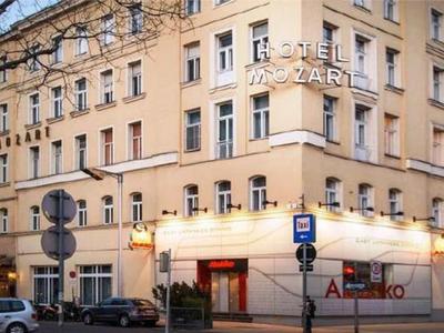 Eckgebäude mit hellgelber Fassade, großen Fenstern und mehreren Geschäften im Erdgeschoss bei Dämmerung.