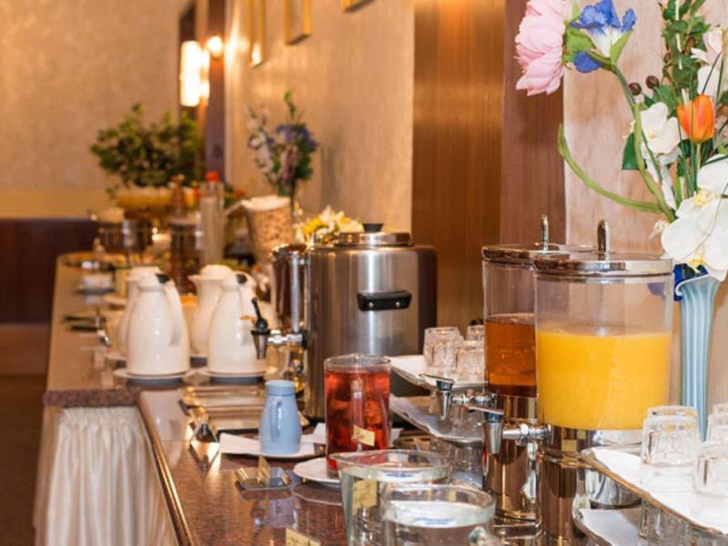 Buffet mit Getränkespendern, Gläsern, Kaffeeautomaten und Blumendekoration in warmem Ambiente.