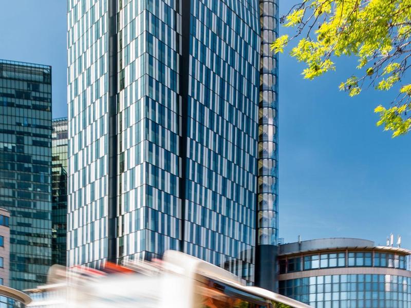 Moderner Wolkenkratzer mit Muster vor klarem Himmel und Bus in Bewegung