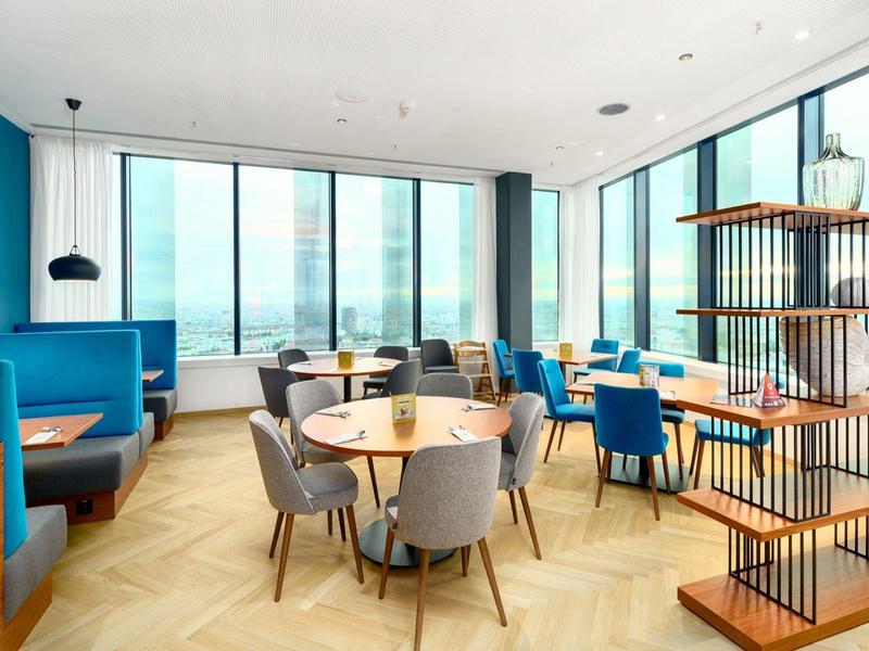 Modern eingerichteter Essbereich mit großen Fenstern und blau-grauen Stühlen