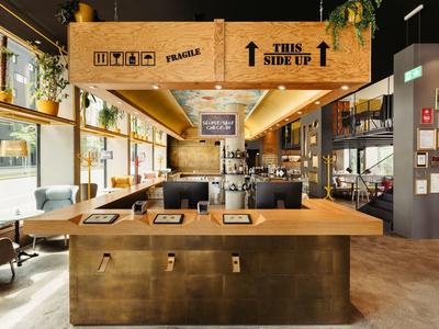 Moderner Café-Innenraum mit Holztresen, bequemen Sitzplätzen und großen Fenstern für viel Tageslicht.