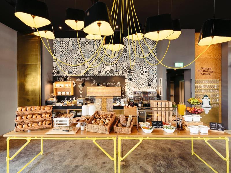 Buffet mit verschiedenen Frühstücksoptionen, Holzregalen, Lampen und moderner Dekoration.