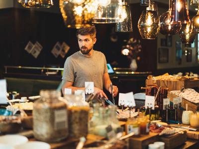 Mężczyzna stoi za bufetem w przytulnej restauracji z ciepłym oświetleniem.