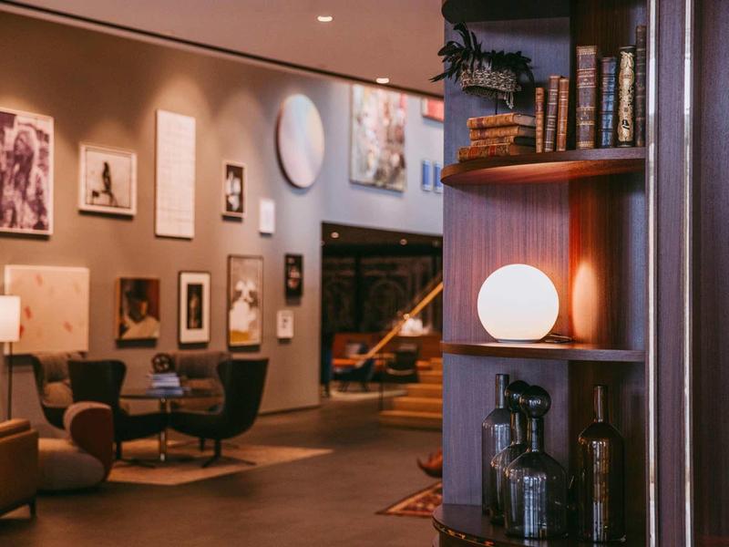 Przytulna strefa lounge w hotelu z fotelami, dziełami sztuki i ciepłym oświetleniem.