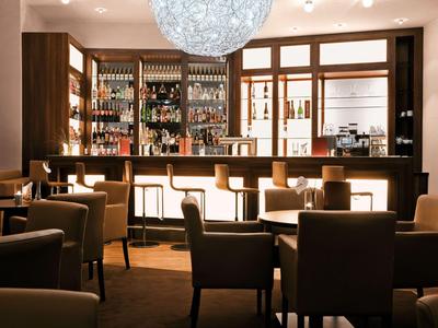 Przytulny bar hotelowy z drewnianym barem, krzesłami i ciepłym oświetleniem.