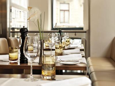 Eleganckie wnętrze restauracji z nakrytymi stołami i wygodnymi ławkami przy dużych oknach.