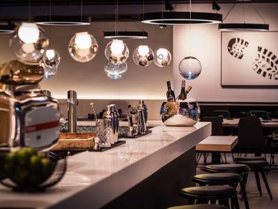 Espace bar d'hôtel moderne avec lampes suspendues élégantes et sièges au comptoir.