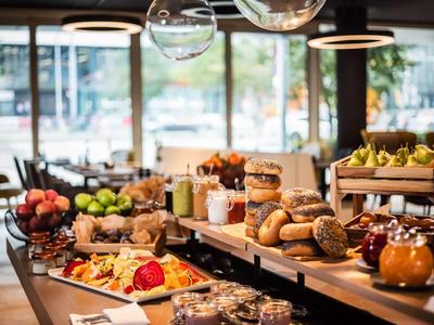 Buffet met verschillende gebakjes, fruit en vleeswaren in een lichte restaurantomgeving.