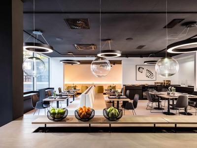 Restaurant moderne avec grandes fenêtres, lampes rondes et espaces d'assise élégants.