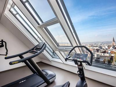 Équipement de fitness moderne devant de grandes fenêtres de toit avec vue sur la ville.