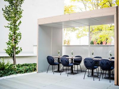 Moderne buitenzitruimte met donkerblauwe stoelen en tafels onder een overdekte structuur.