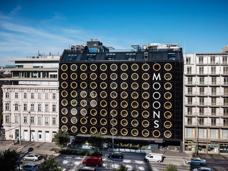 Modern hotelgebouw met opvallende gevel van gouden cirkels en het opschrift MOOD MOONS.