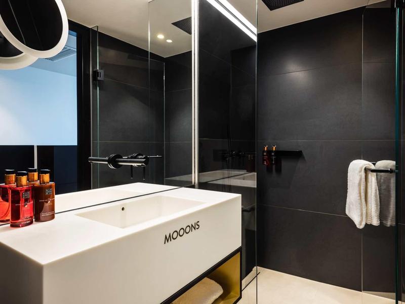 Moderne badkamer met een witte wastafel, zwarte muren en rode verzorgingsflessen.