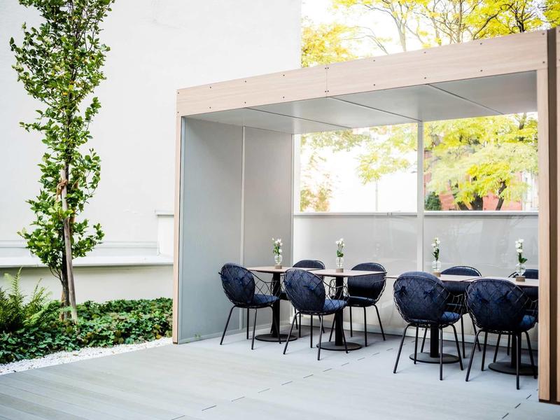 Moderne buitenzitruimte met donkerblauwe stoelen en tafels onder een overdekte structuur.